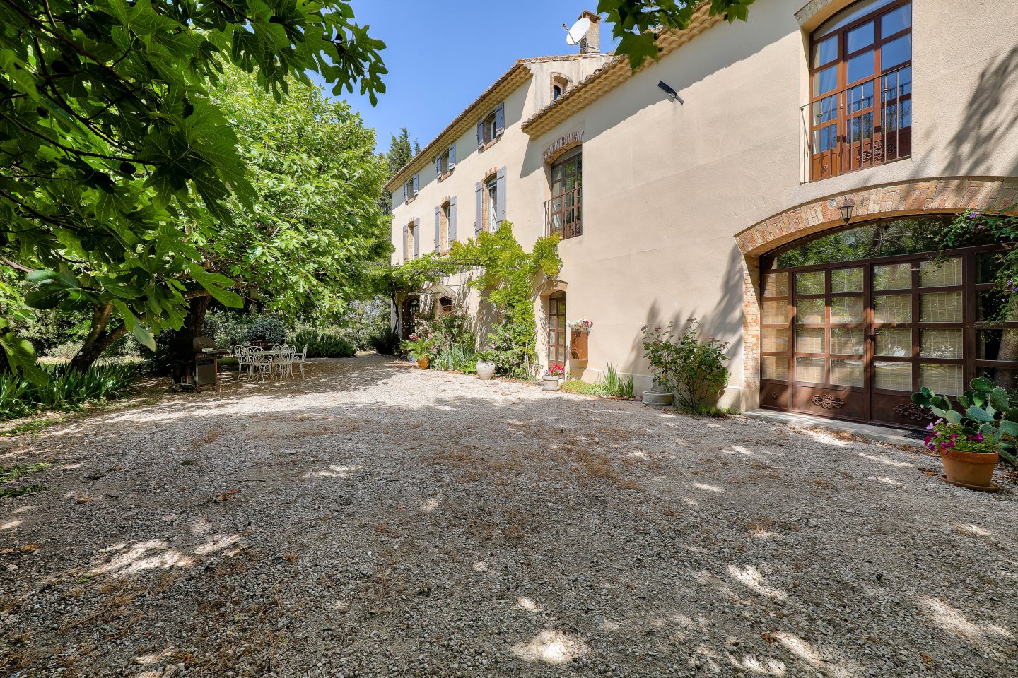 La cour gravillonnée et la façade du Mas de la Souvine