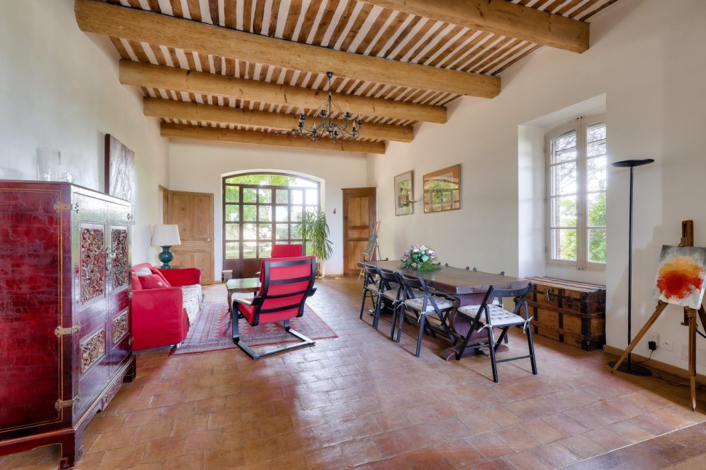 Le salon : canapé, fauteuils et grande table sous les poutres